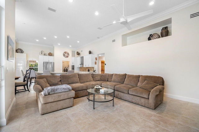 living room featuring ceiling fan, light tile patterned floors, ornamental molding, and a towering ceiling