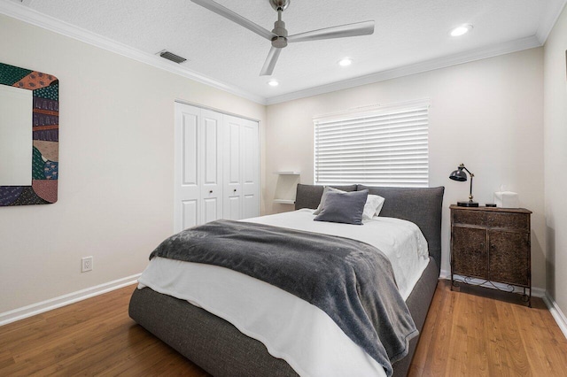 bedroom with hardwood / wood-style floors, a textured ceiling, ceiling fan, crown molding, and a closet