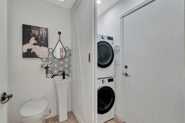 laundry area featuring stacked washer / drying machine and light tile patterned flooring