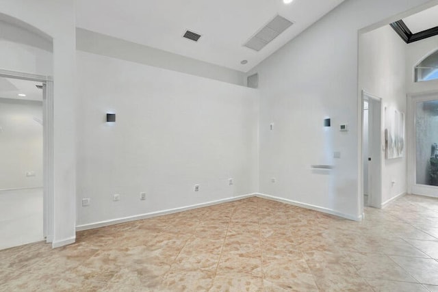 empty room with a towering ceiling and light tile patterned floors