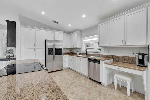 kitchen with stainless steel appliances, sink, vaulted ceiling, white cabinetry, and light stone counters