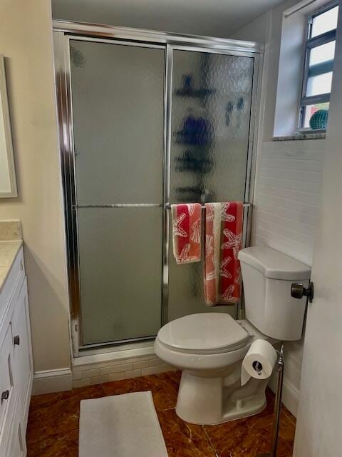 bathroom with tile patterned flooring, an enclosed shower, vanity, and toilet