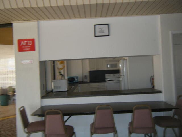 kitchen with white appliances, kitchen peninsula, and a kitchen breakfast bar