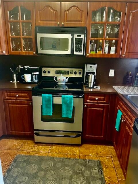 kitchen featuring decorative backsplash, appliances with stainless steel finishes, and light tile patterned floors