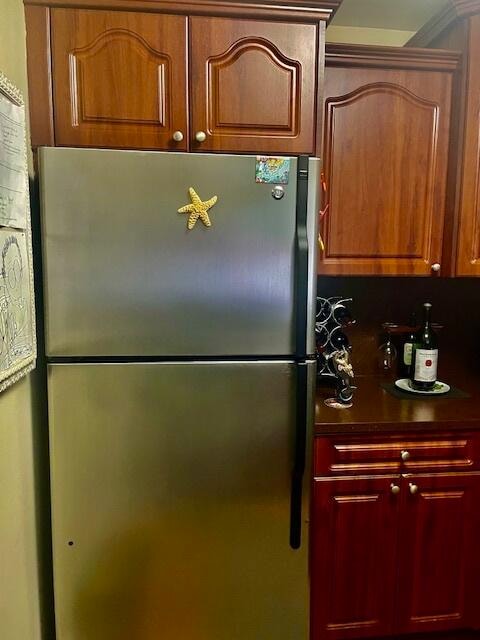 kitchen with stainless steel refrigerator and crown molding