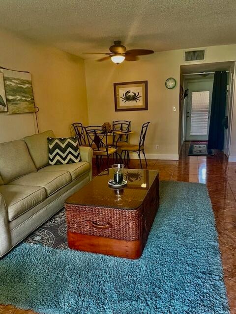 living room featuring a textured ceiling, tile patterned flooring, and ceiling fan