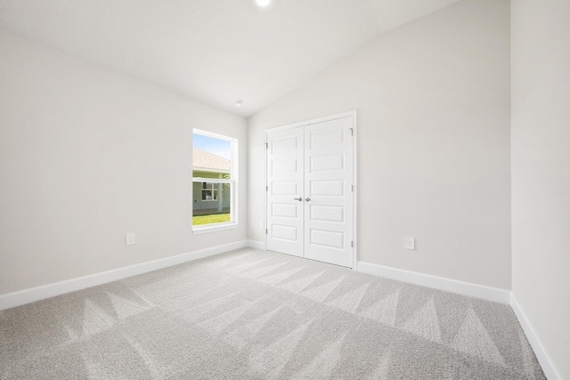 unfurnished bedroom featuring carpet flooring, vaulted ceiling, and a closet