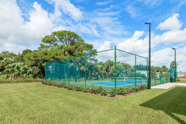 view of tennis court featuring a lawn