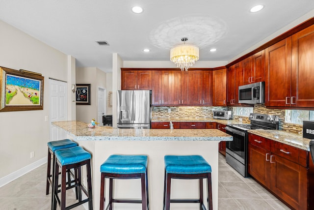 kitchen with hanging light fixtures, light stone counters, a notable chandelier, a breakfast bar, and appliances with stainless steel finishes