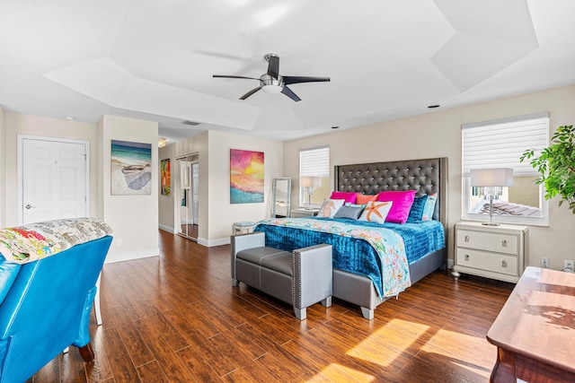 bedroom with hardwood / wood-style floors, ceiling fan, and a raised ceiling