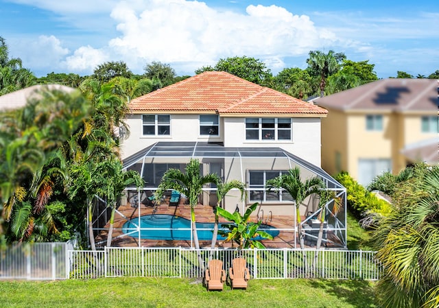 rear view of property with a lanai, a patio area, a lawn, and a fenced in pool