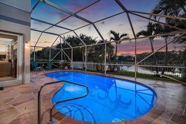 pool at dusk with a lanai, a patio area, and a water view