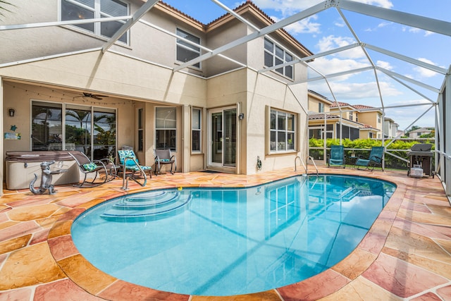 view of swimming pool with glass enclosure, a patio area, ceiling fan, and grilling area