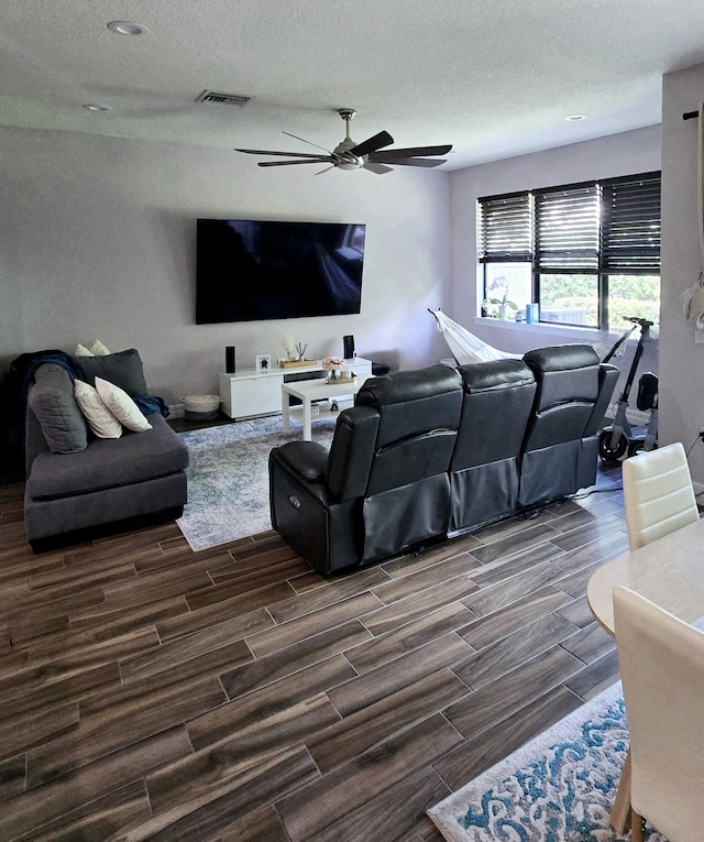 living room featuring ceiling fan, dark hardwood / wood-style floors, and a textured ceiling