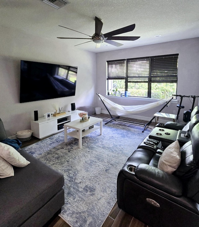 living room with ceiling fan, dark wood-type flooring, and a textured ceiling