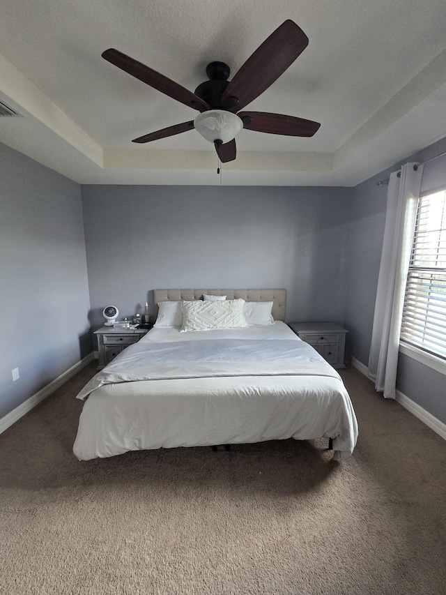 bedroom featuring ceiling fan, a raised ceiling, and carpet flooring