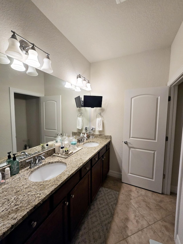 bathroom with a textured ceiling, tile patterned flooring, and vanity