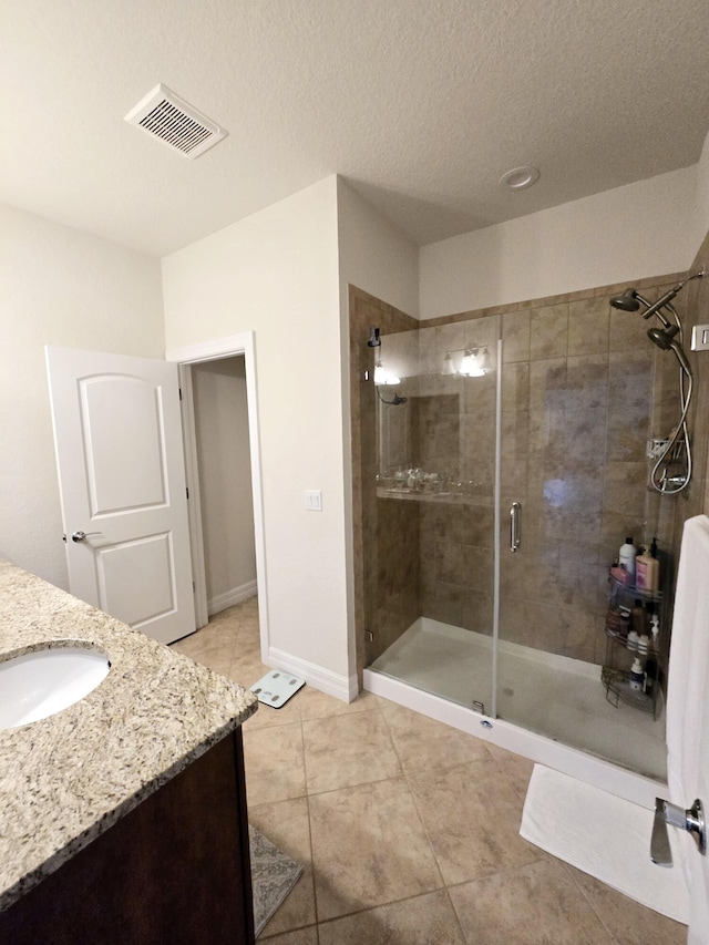 bathroom featuring tile patterned flooring, an enclosed shower, vanity, and a textured ceiling