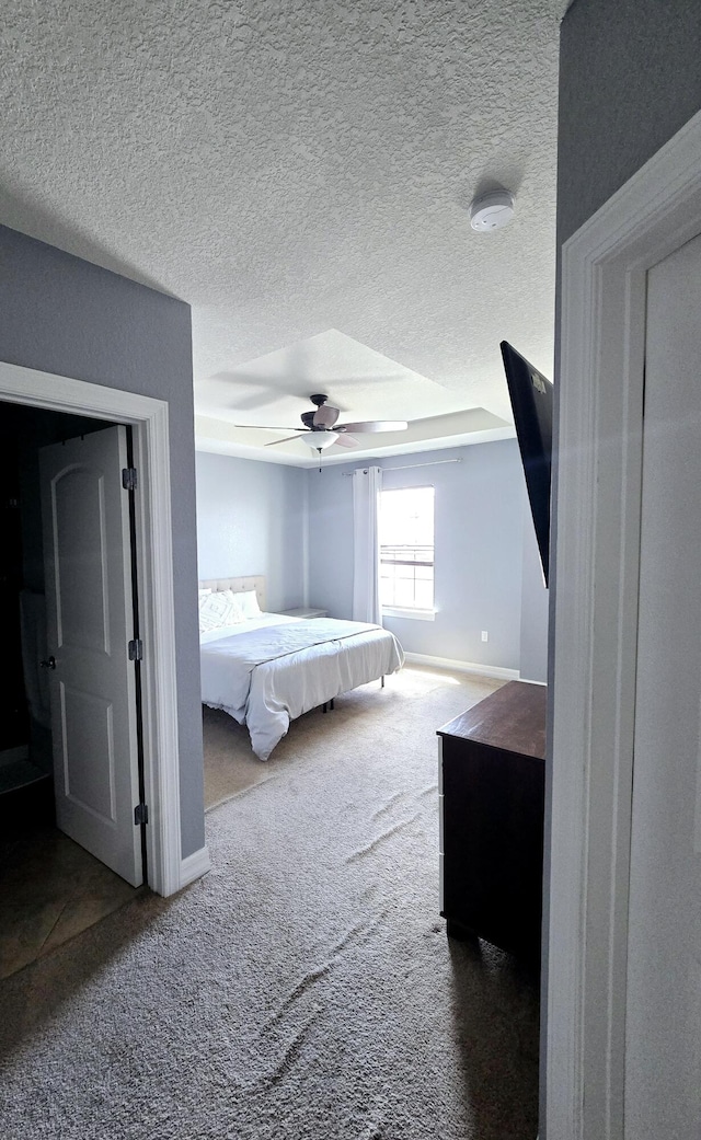 carpeted bedroom with ceiling fan and a textured ceiling