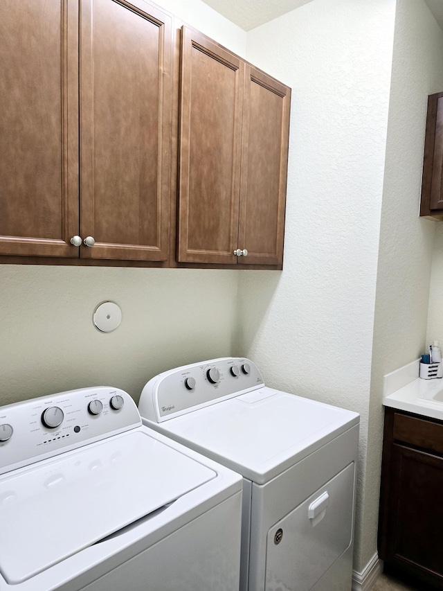 laundry room featuring washing machine and clothes dryer and cabinets