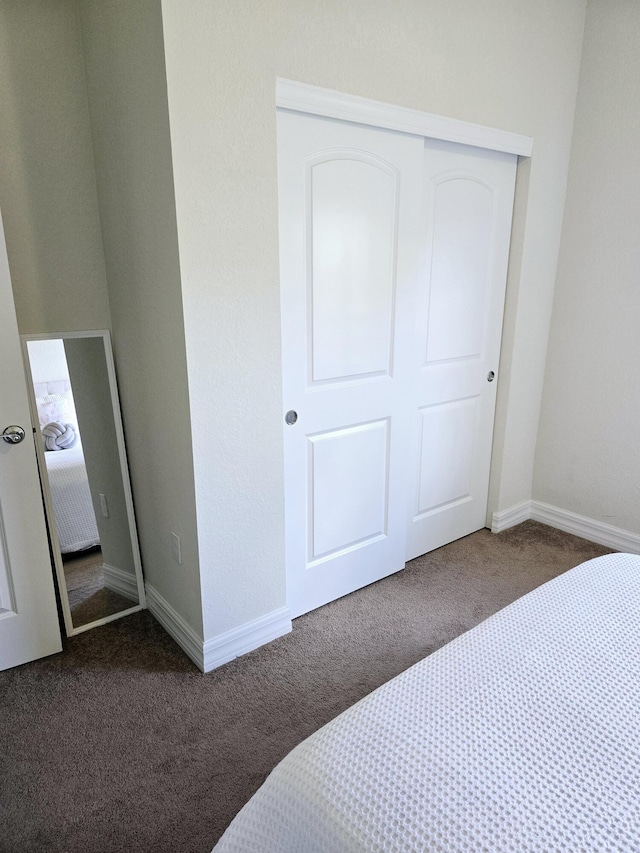 bedroom with dark carpet and a closet