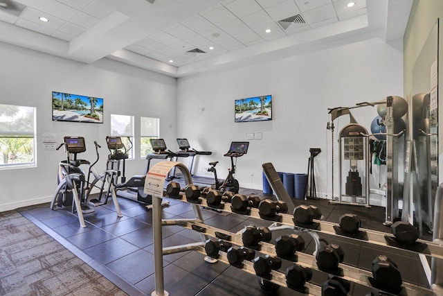 gym featuring a drop ceiling, a towering ceiling, and a healthy amount of sunlight