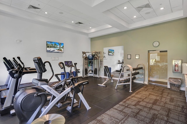 gym featuring a high ceiling and a tray ceiling