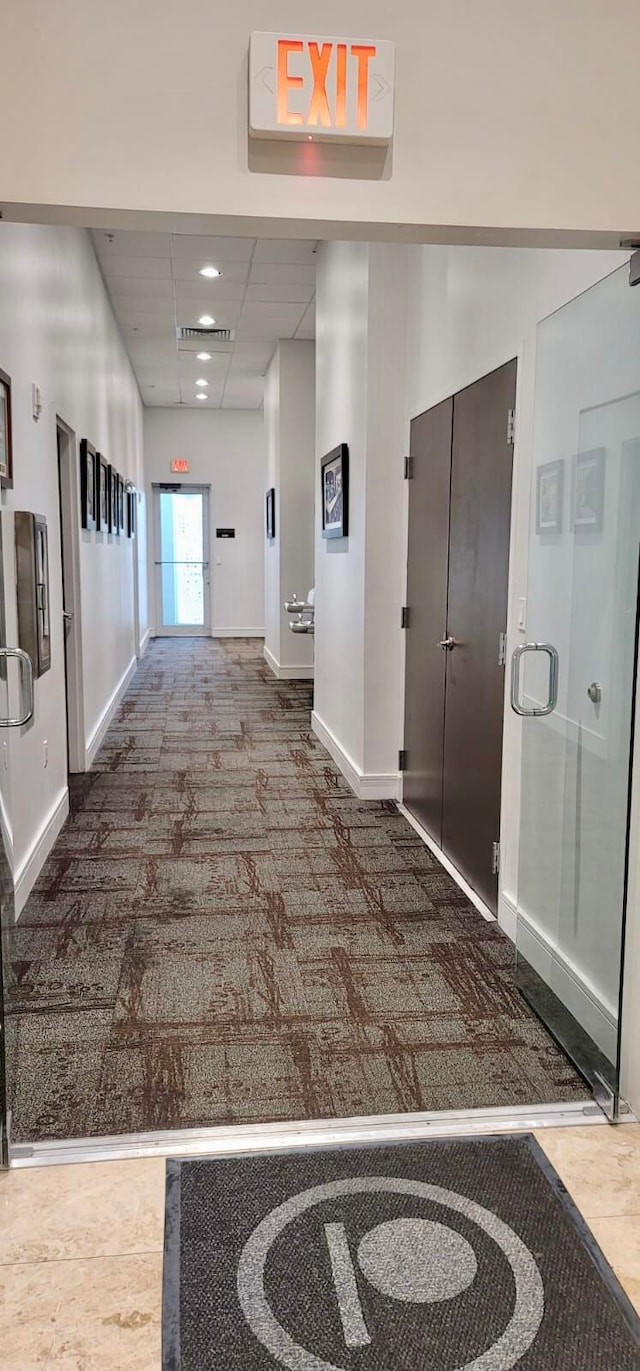 corridor featuring a paneled ceiling and carpet