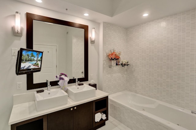 bathroom featuring tile patterned flooring, tiled tub, and vanity