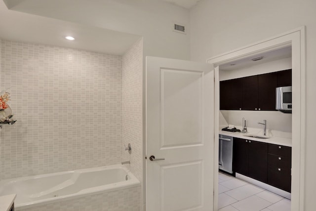 bathroom featuring tile patterned floors, tiled bath, and vanity