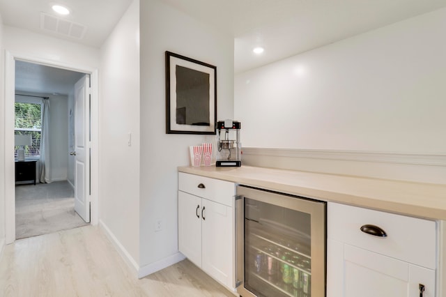 bar featuring white cabinets, light hardwood / wood-style floors, and beverage cooler