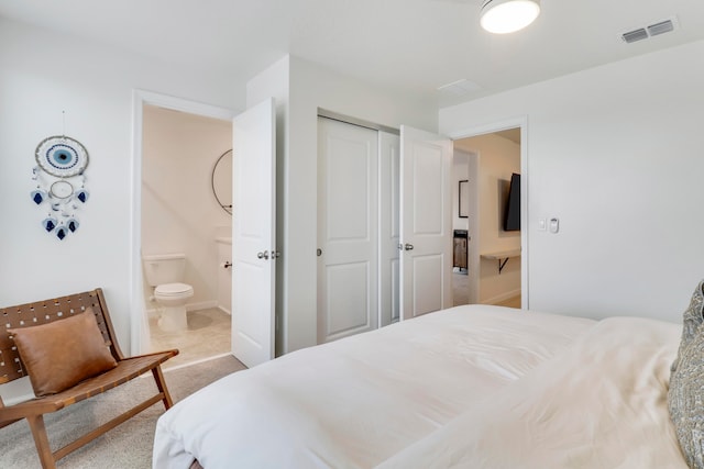 bedroom with light colored carpet, a closet, and ensuite bath