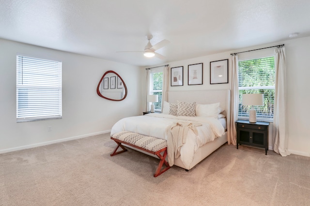 bedroom with light carpet, multiple windows, and ceiling fan