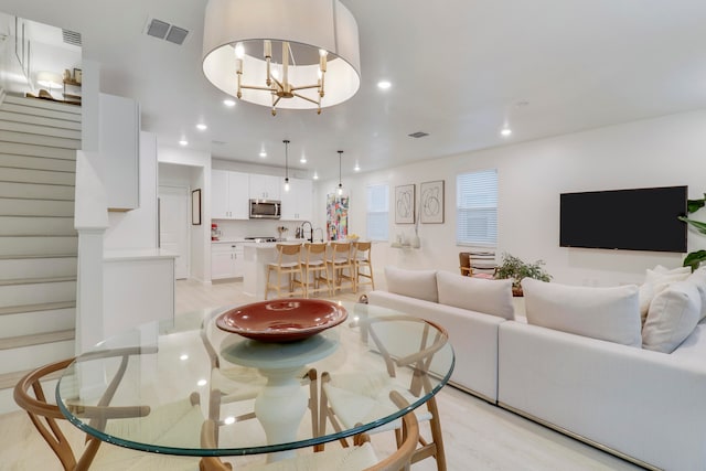 dining area with sink, a chandelier, and light wood-type flooring