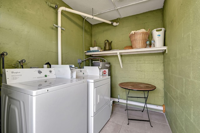 clothes washing area featuring light tile patterned floors, washer and dryer, and electric water heater