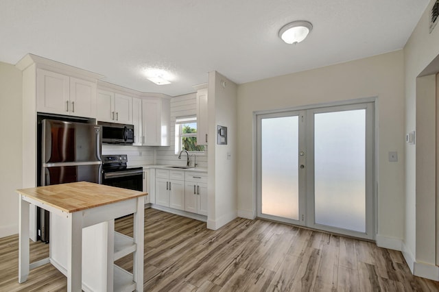 kitchen with light hardwood / wood-style flooring, white cabinetry, appliances with stainless steel finishes, and sink