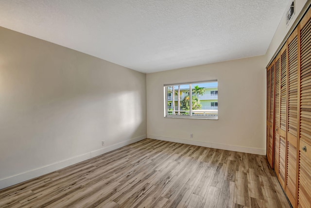 unfurnished bedroom with light hardwood / wood-style flooring, a closet, and a textured ceiling