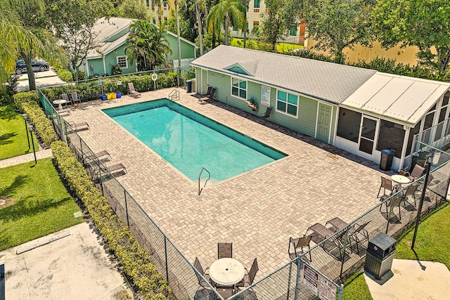 view of swimming pool featuring a sunroom and a patio area