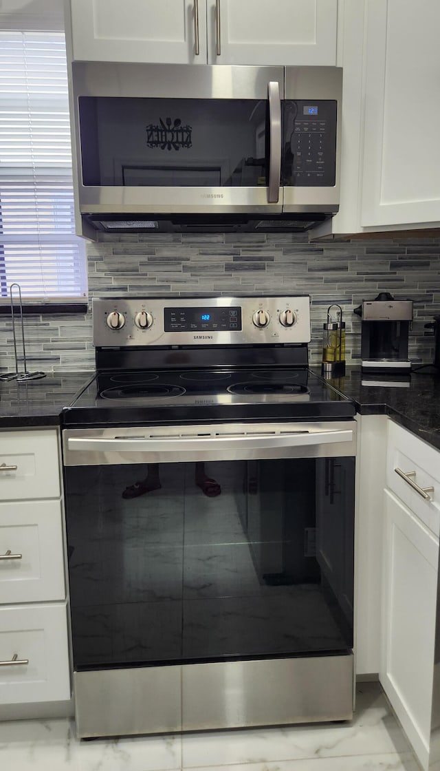 kitchen with appliances with stainless steel finishes, white cabinetry, and backsplash