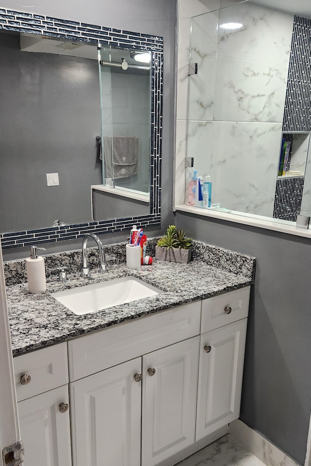 bathroom with a tile shower and vanity