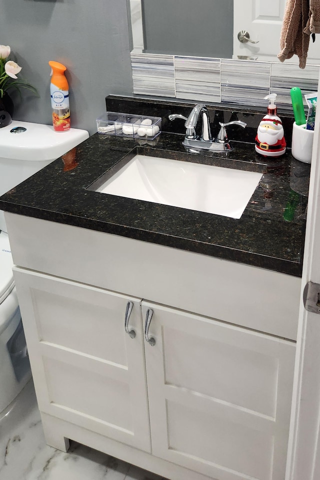 bathroom with decorative backsplash, vanity, and toilet