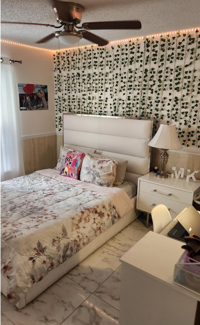 bedroom with ceiling fan, wood walls, and a textured ceiling