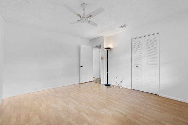 unfurnished bedroom featuring a closet, light hardwood / wood-style floors, ceiling fan, and a textured ceiling