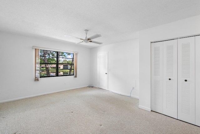 unfurnished bedroom with ceiling fan, a textured ceiling, and light carpet