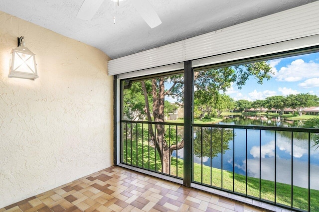 unfurnished sunroom with a water view and ceiling fan