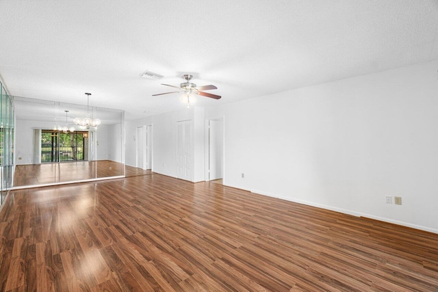 interior space featuring ceiling fan with notable chandelier, a textured ceiling, and dark wood-type flooring