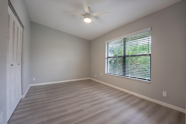 unfurnished bedroom featuring ceiling fan, a closet, and light wood-type flooring