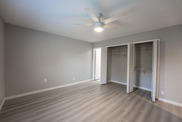 unfurnished bedroom with two closets, ceiling fan, and light hardwood / wood-style flooring