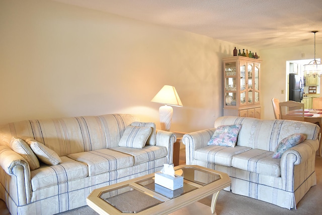 living room with carpet, a textured ceiling, and a chandelier