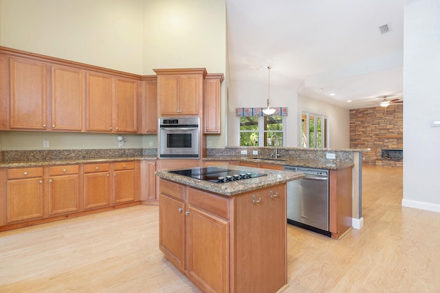 kitchen with light hardwood / wood-style floors, a center island, sink, appliances with stainless steel finishes, and ceiling fan